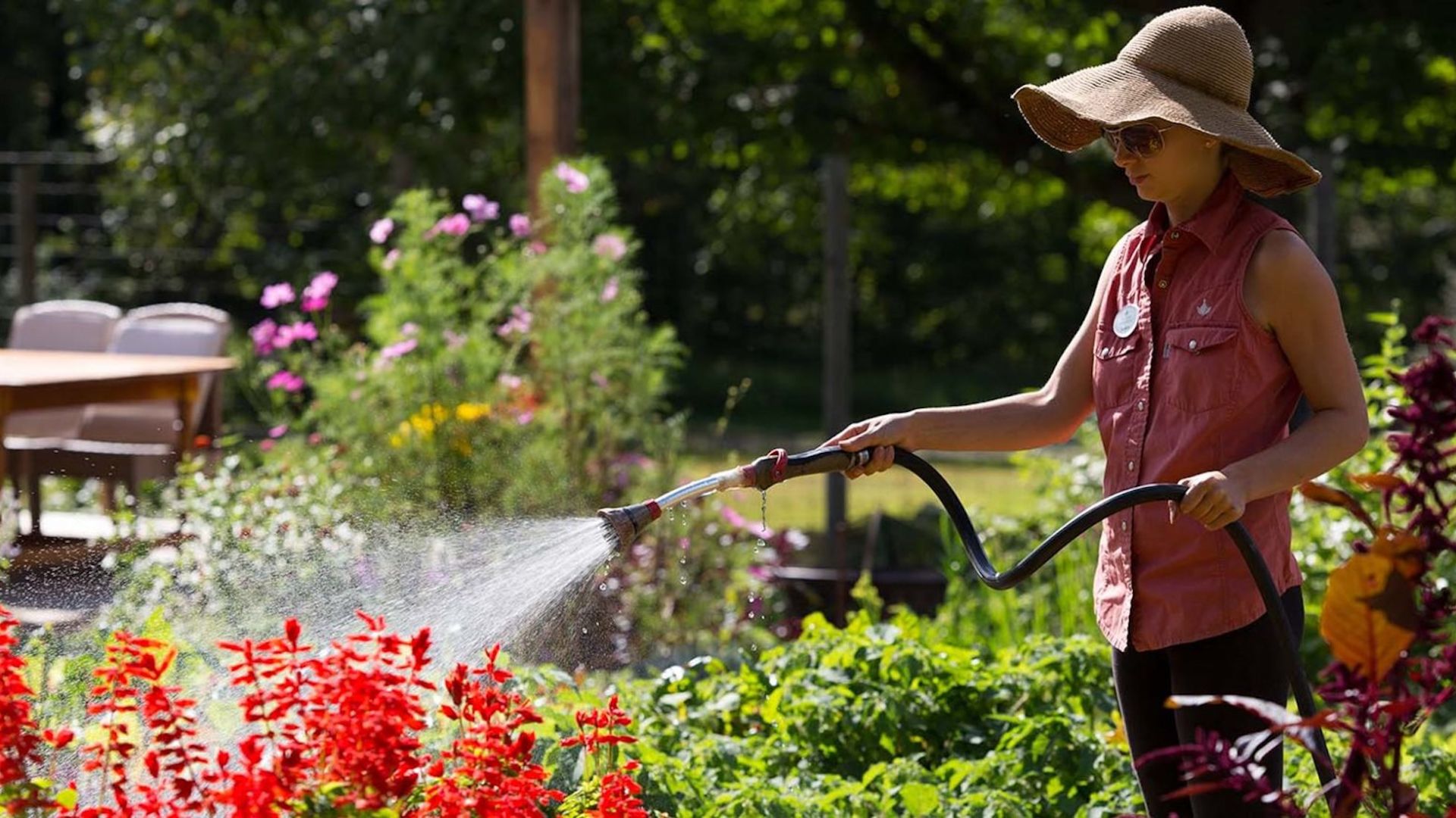 A woman watering flowers and plants in a garden at The Lodge at Woodloch