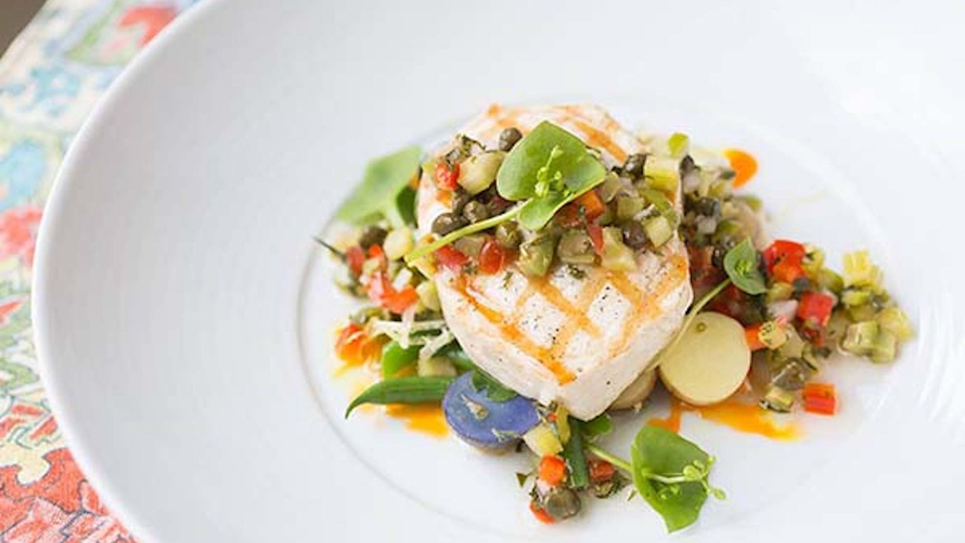 Grilled Swordfish Nicoise on a White Plate on a colorful placemat