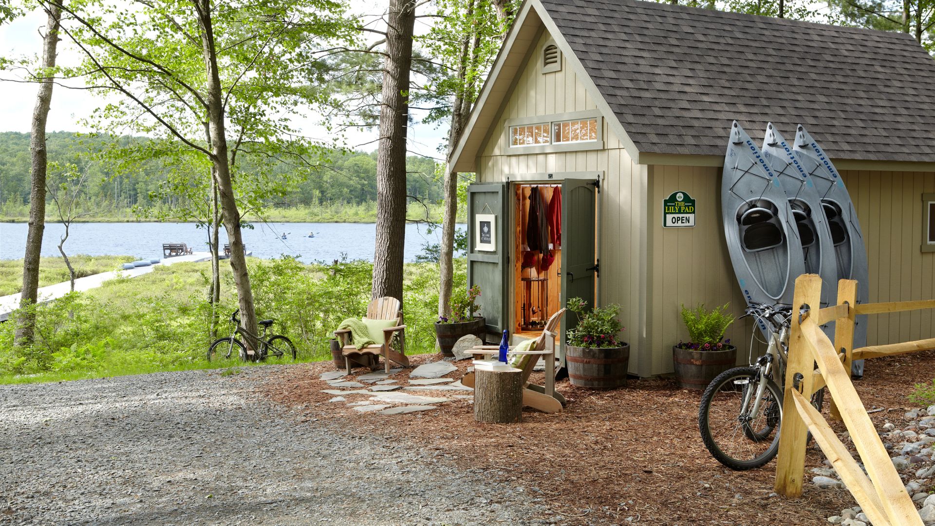 Building with open doors and kayaks, bikes, and outdoor adventure equipment available for use next to the lake