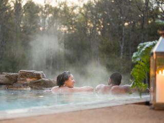 A couple in the Horizon Edge Whirlpool at The Lodge at Woodloch looking at each other by the forests edge