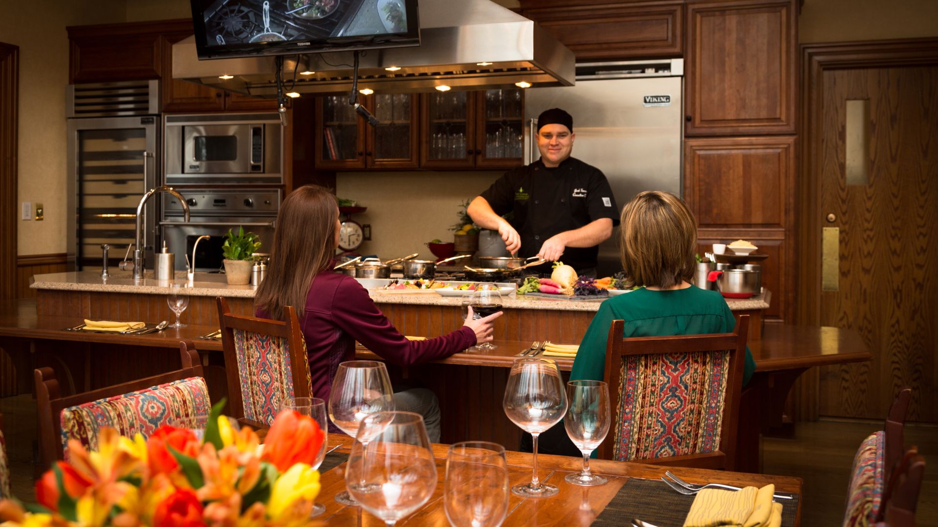 A cooking demonstration attended by two women in the Demo Kitchen at The Lodge at Woodloch