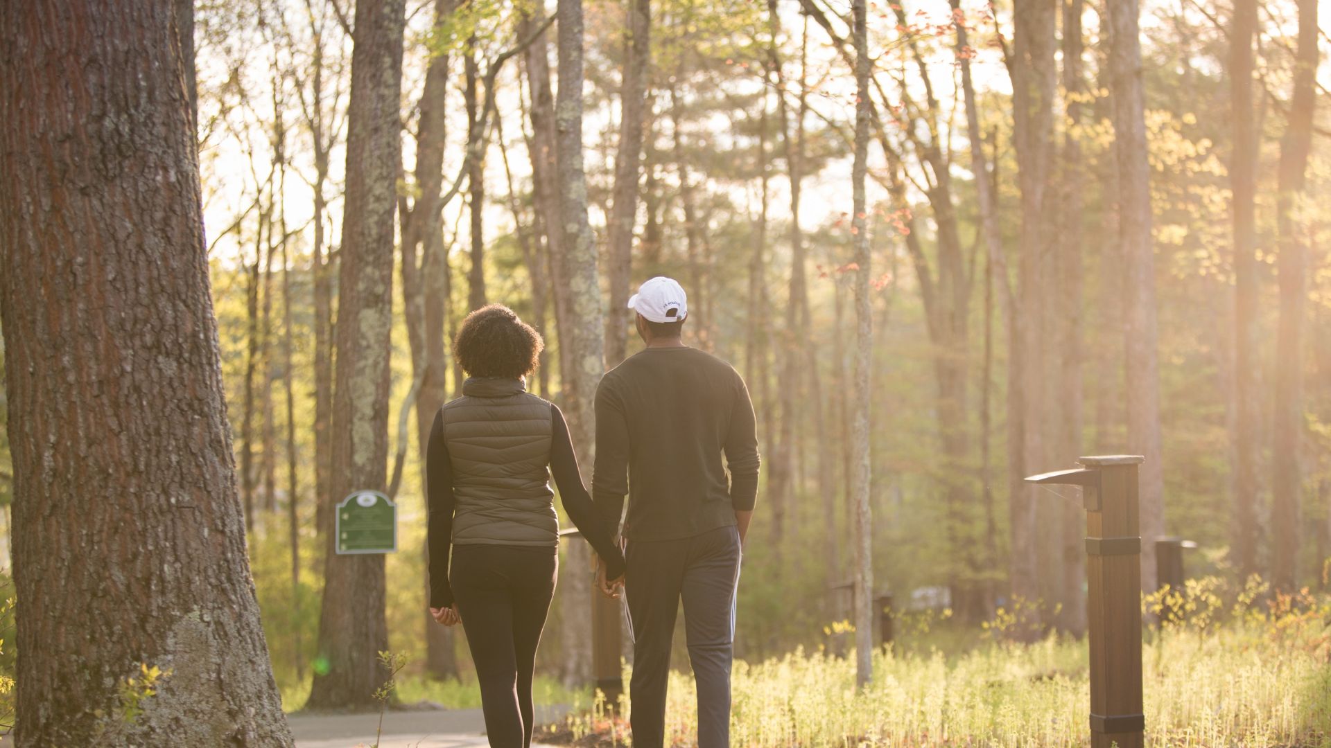 A couple holding hands and embarking on a sunrise walk on the nature trails at The Lodge at Woodloch