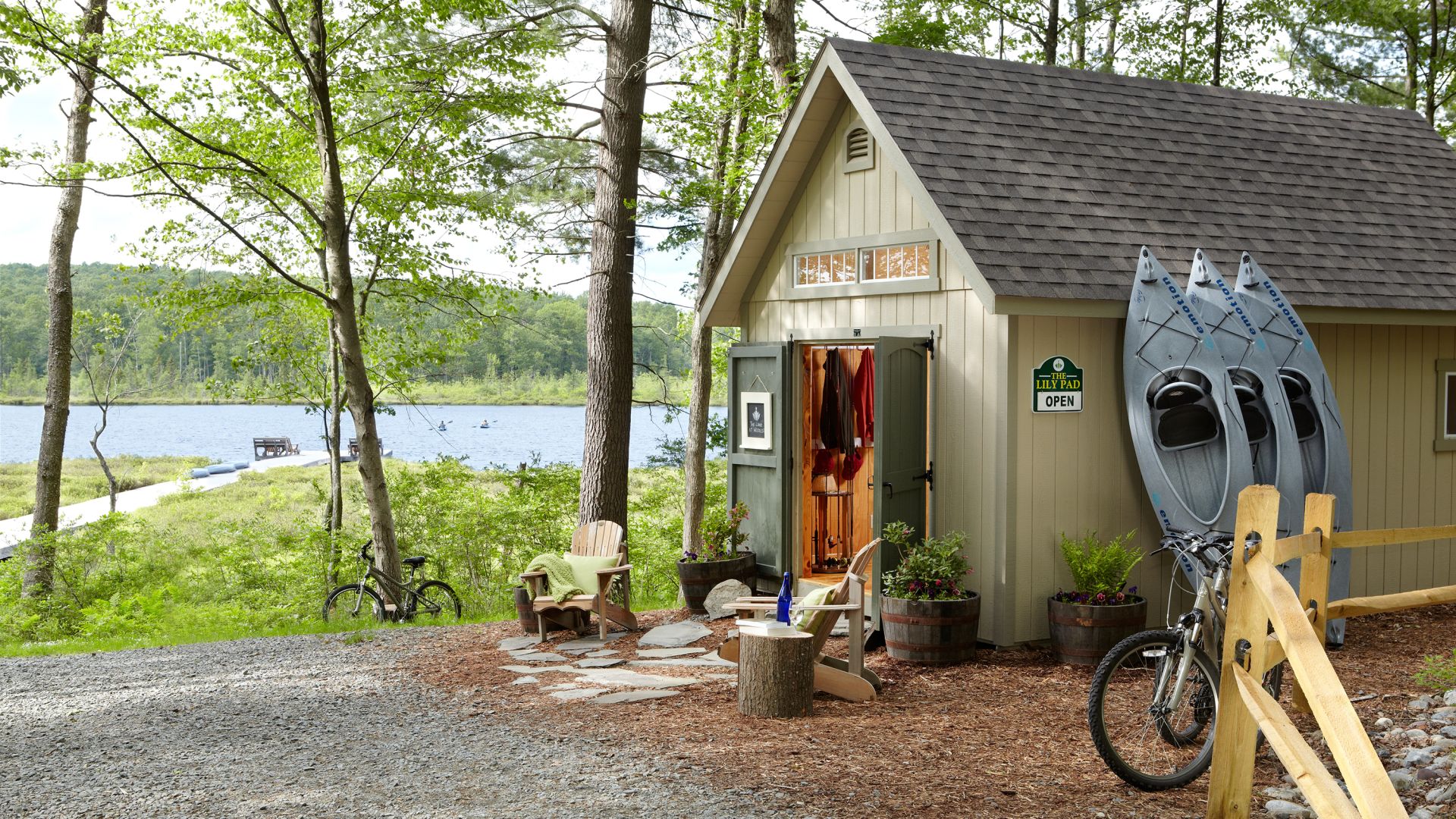 Building with open doors and kayaks, bikes, and outdoor adventure equipment available for use next to the lake