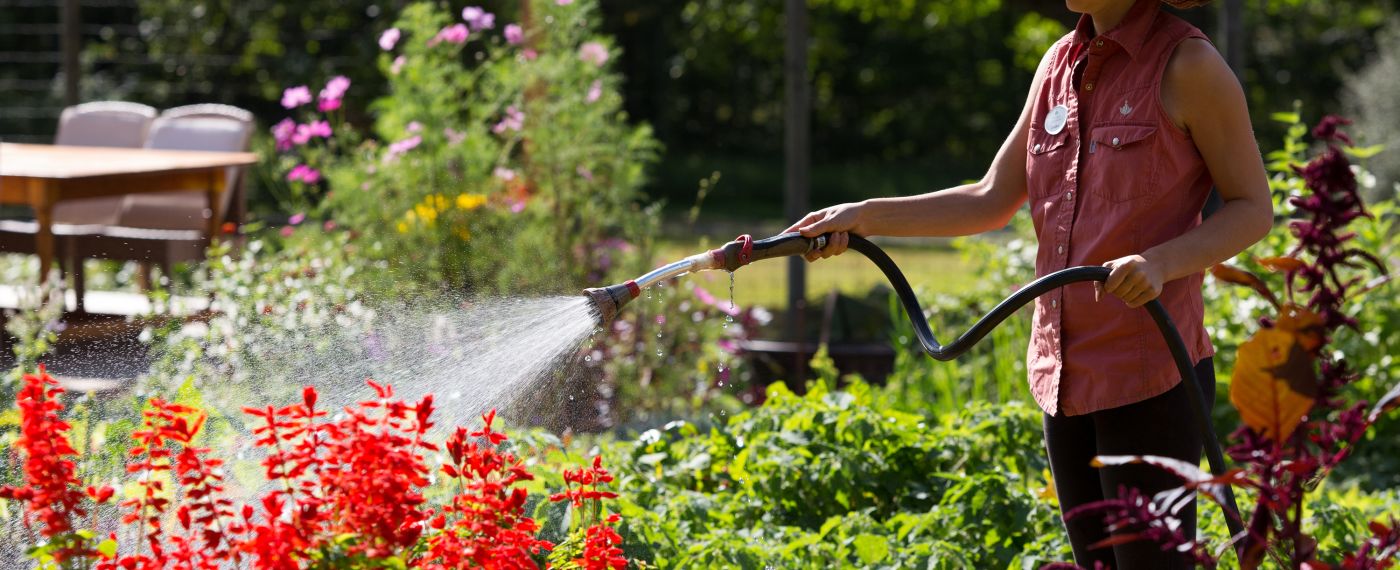 A woman watering flowers and plants in a garden at The Lodge at Woodloch