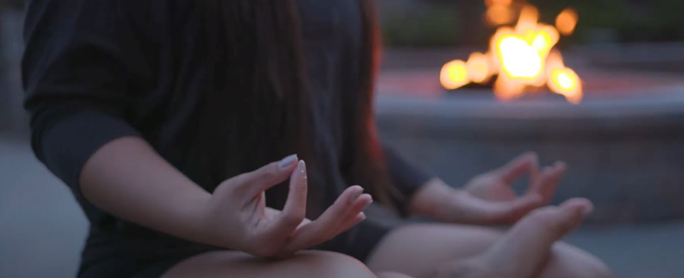 A close up of a woman's hand while she meditates by an outside firepit at The Lodge at Woodloch